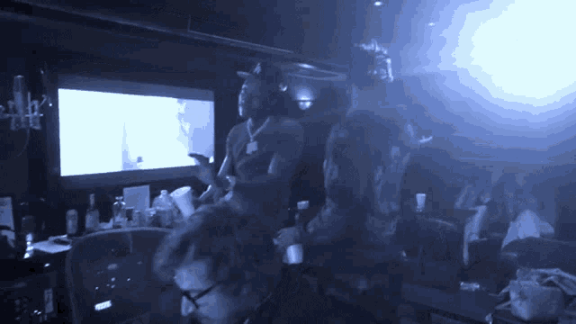 a group of people sitting in a dark room with a blue light shining on them