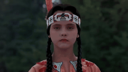 a young girl in a native american costume is wearing a headband with feathers on it .