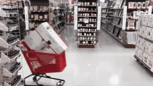 a red shopping cart filled with boxes in a store aisle