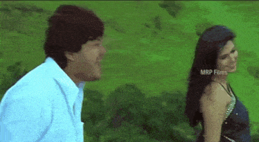 a man and a woman are standing next to each other on a green field .