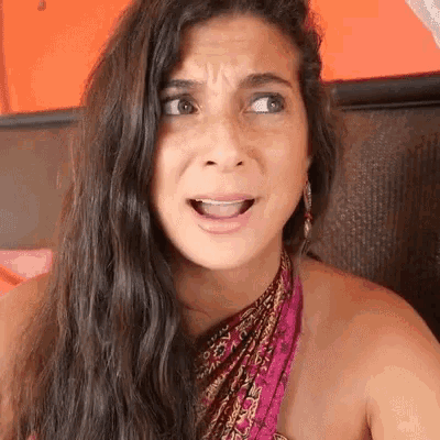 a woman with long hair and a scarf around her neck is making a funny face .