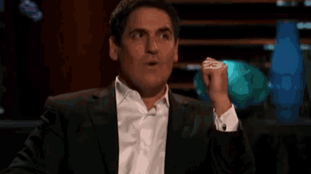 a man in a suit and white shirt is making a funny face while holding something in his hand .