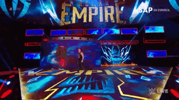 a man is standing on a stage in front of a large sign that says empire