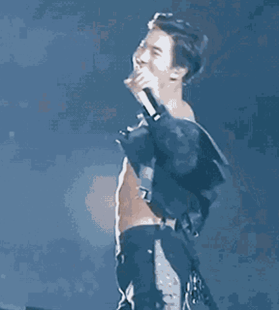 a shirtless man is holding a microphone and laughing .