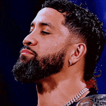 a close up of a man with a beard wearing earrings and a necklace .
