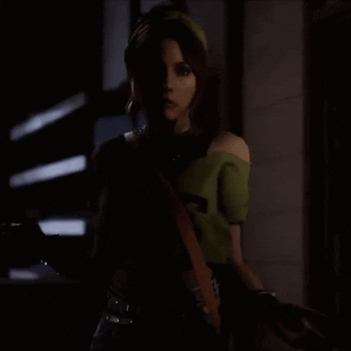 a woman in a green shirt is standing in the dark .