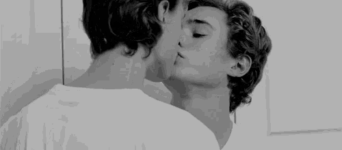 a couple of young men are kissing each other in a black and white photo .