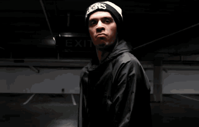 a man wearing a black jacket and a beanie that says kings on it