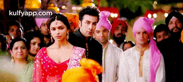 a man and a woman are standing in front of a crowd of people at a wedding .