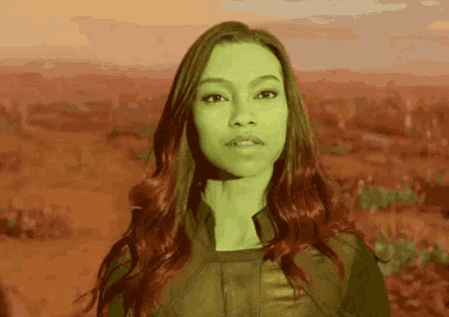 a woman with red hair and green eyes is standing in front of a field .