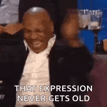 a man in a suit and tie is laughing while sitting at a table .