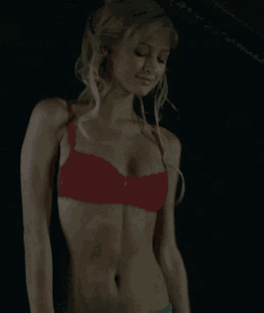 a woman in a red bra and blue shorts is standing in a dark room
