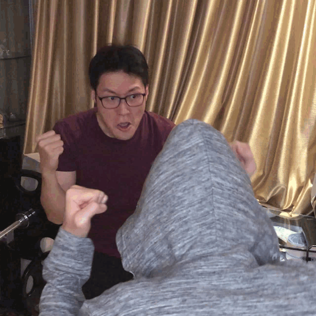 a man wearing glasses and a hoodie is making a face