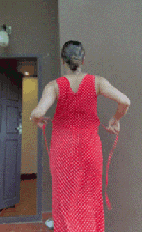 a woman in a red polka dot dress is standing