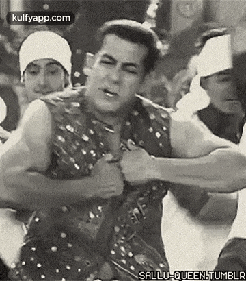 a black and white photo of a man flexing his muscles in a crowd .