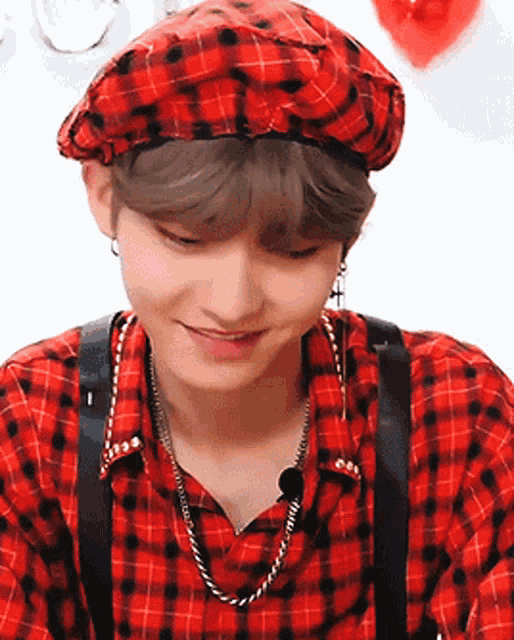 a man wearing a red plaid shirt and a red hat is smiling