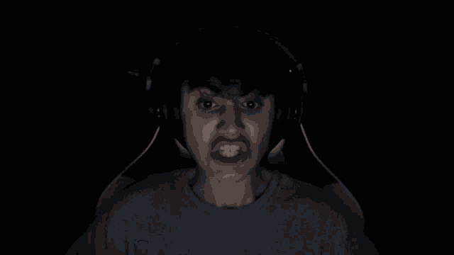 a person wearing headphones is making a funny face in the dark