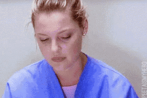 a close up of a woman wearing a blue scrub with her eyes closed
