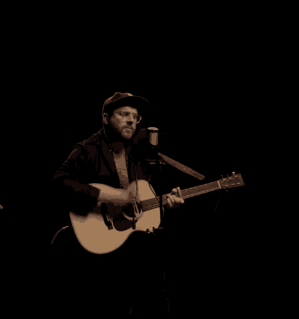 a man is singing into a microphone while playing a guitar