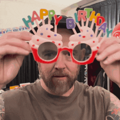 a man with a beard wears a pair of glasses that say happy birthday