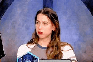 a woman with long hair is sitting in front of a blue wall and holding a tablet .