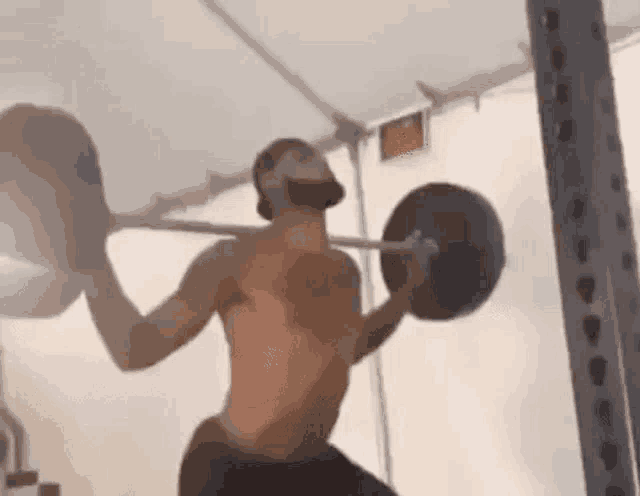 a man is lifting a barbell in a gym .