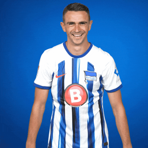 a man is wearing a blue and white striped shirt with the letter b on it
