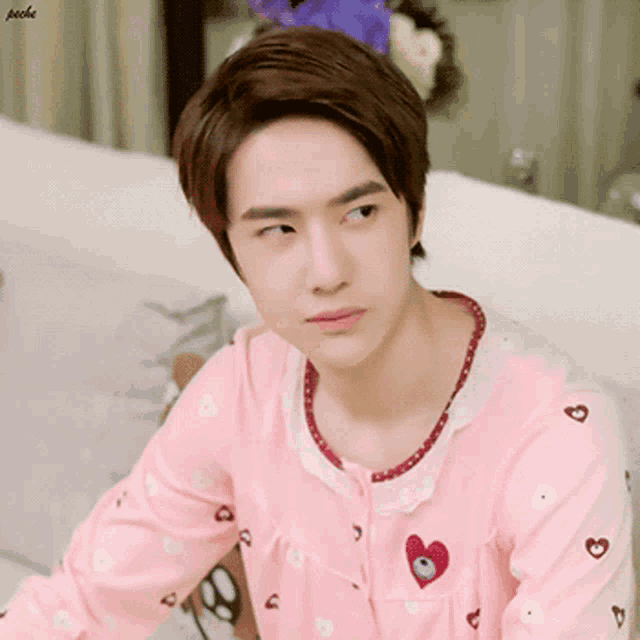 a young man in a pink pajama top with hearts on it