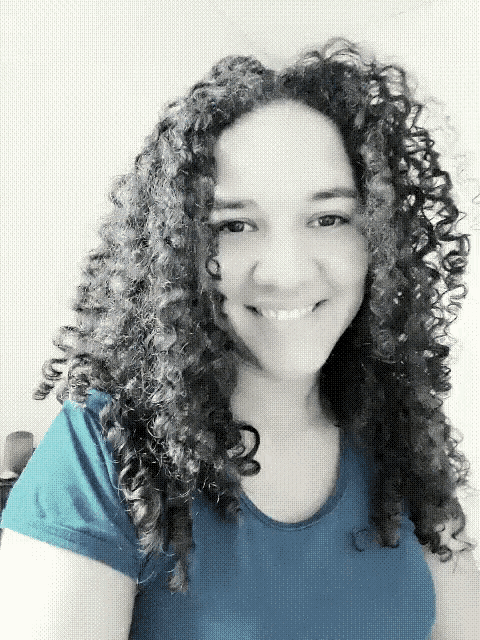 a woman with curly hair wearing a blue shirt is smiling