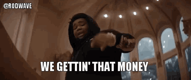 a man in a hoodie is pointing at the camera and saying `` we gettin that money '' .