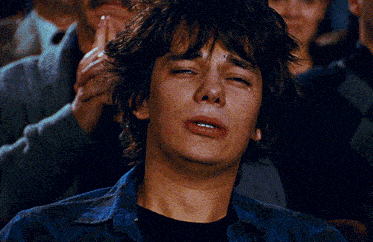 a young man is crying while sitting in a crowd of people