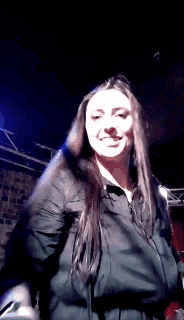 a woman in a black jacket is smiling and looking at the camera