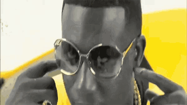 a close up of a man wearing glasses and a gold chain around his neck