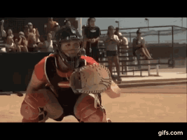 a baseball player wearing a helmet and a catcher 's mitt is catching a ball .