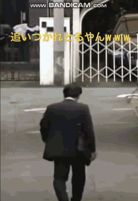 a man in a suit is walking down a street with the words www.bandicam.com on the bottom right