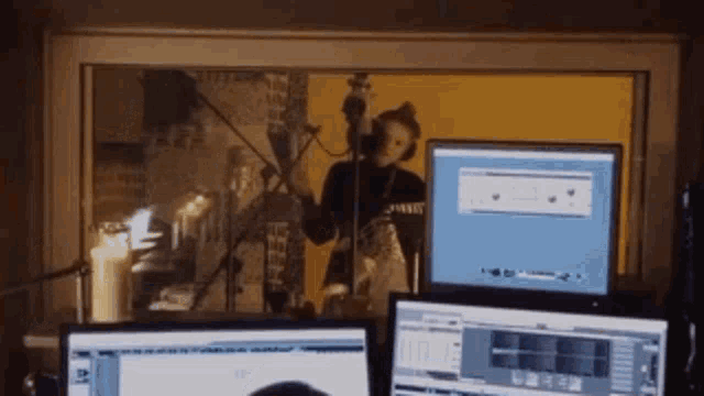a person is singing into a microphone in front of a computer screen