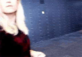 a woman with blonde hair is standing in front of a wall of lockers