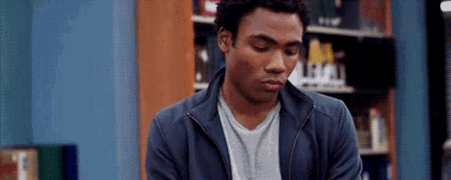 a man is sitting in front of a bookshelf in a library .