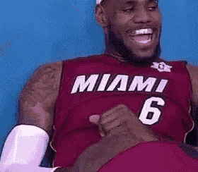 lebron james is wearing a miami 6 jersey and laughing .