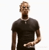 a man wearing sunglasses and a black shirt is standing with his hands outstretched .