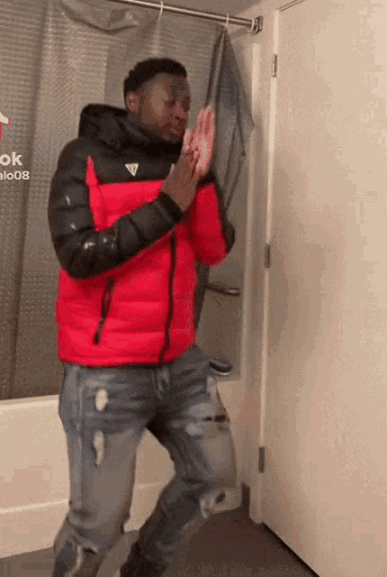 a man in a red jacket is standing in front of a shower curtain