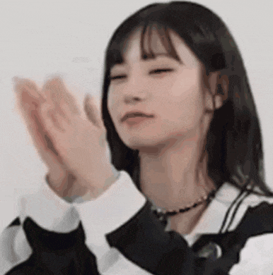 a young woman is clapping her hands in a close up of her face .