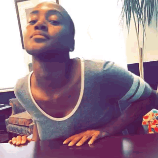 a woman is sitting at a table with her hands on the table and making a funny face .