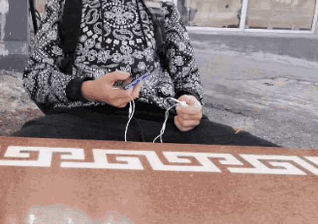 a person is sitting at a table with a greek key pattern