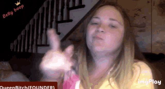 a woman giving a thumbs up in front of a sign that says queen bitch founder