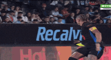 a soccer player is kicking a ball in front of a haier sign