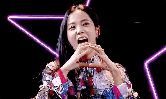 a girl is making a heart shape with her hands in front of a star .