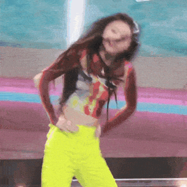 a woman in a red top and yellow pants is dancing on a stage .