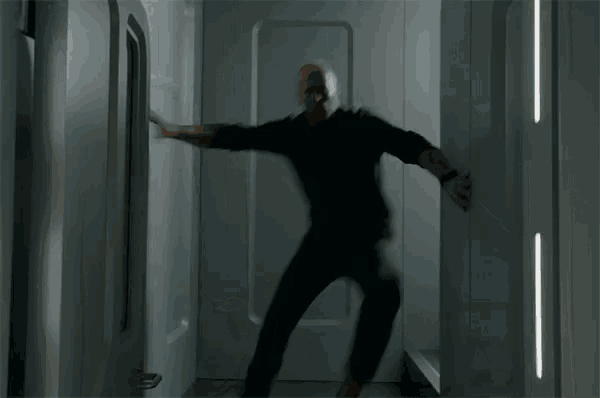 a man in a black shirt is standing in a doorway with his arms outstretched