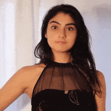 a woman wearing a black dress with a sheer top